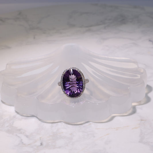 Adjustable Amethyst ring displayed on a shell-shaped crystal stand, showing the vivid purple gemstone.