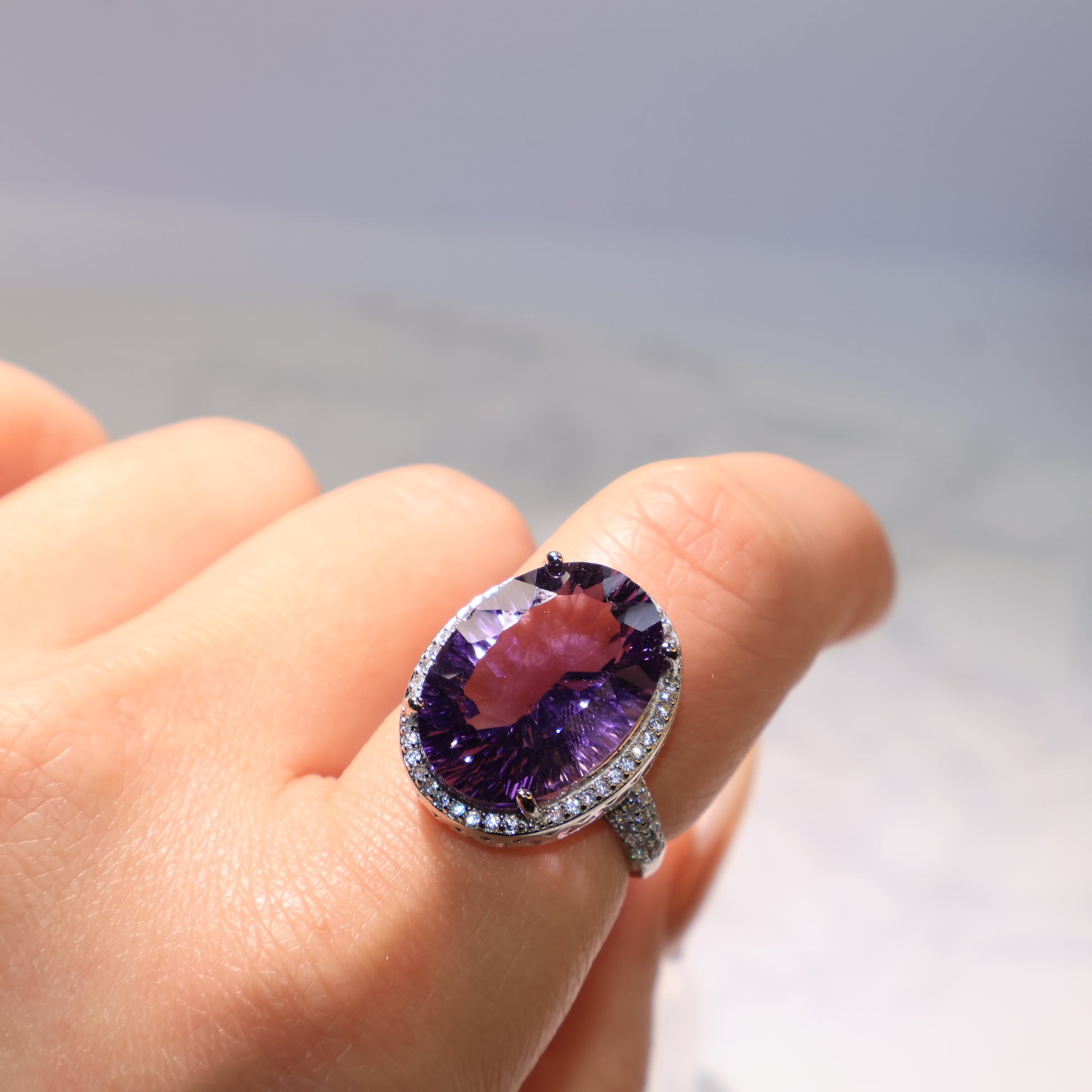 Adjustable Amethyst ring worn on the finger, reflecting radiant purple light.