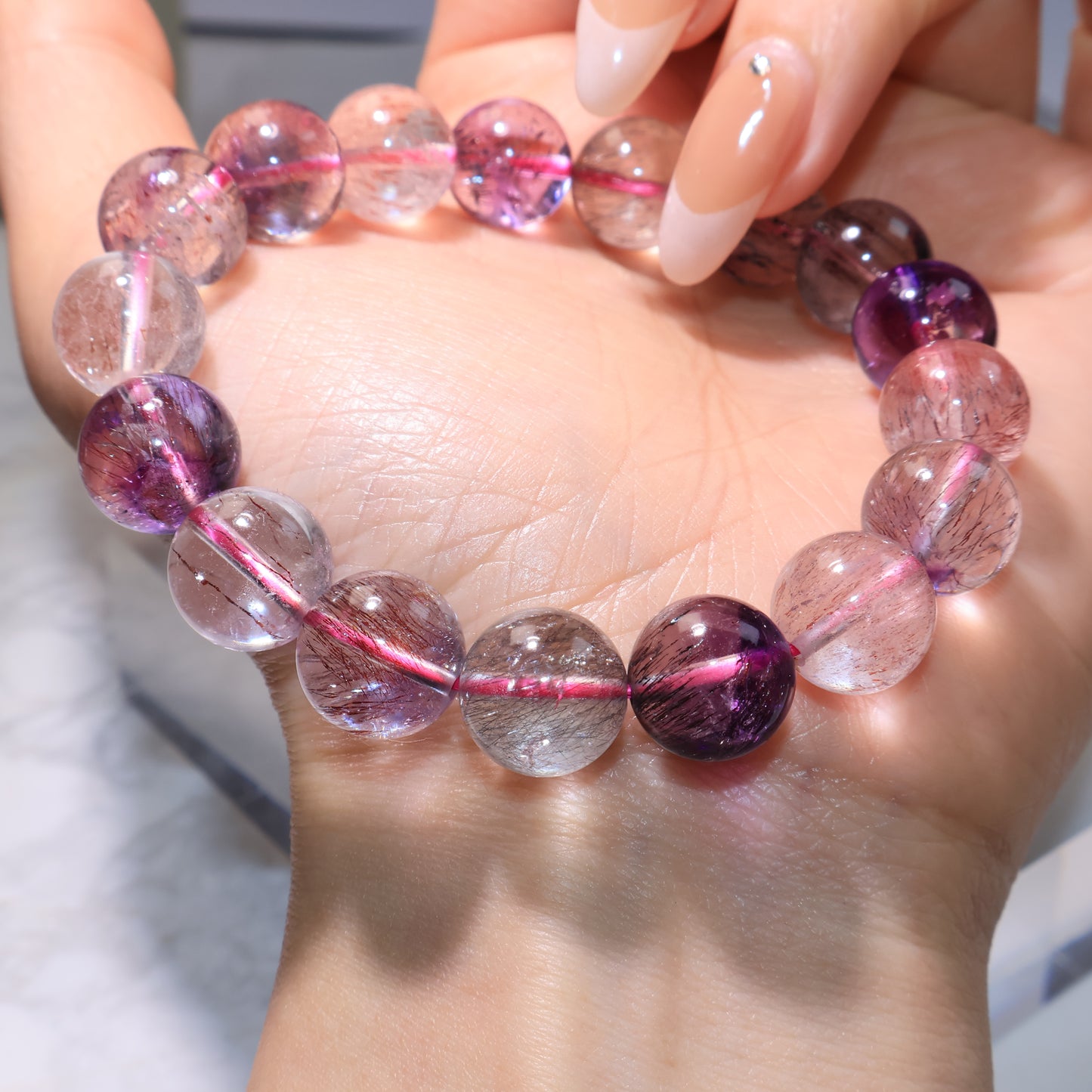 Bracelet resting on palm, showing the natural purple and smoky quartz tones within the beads.