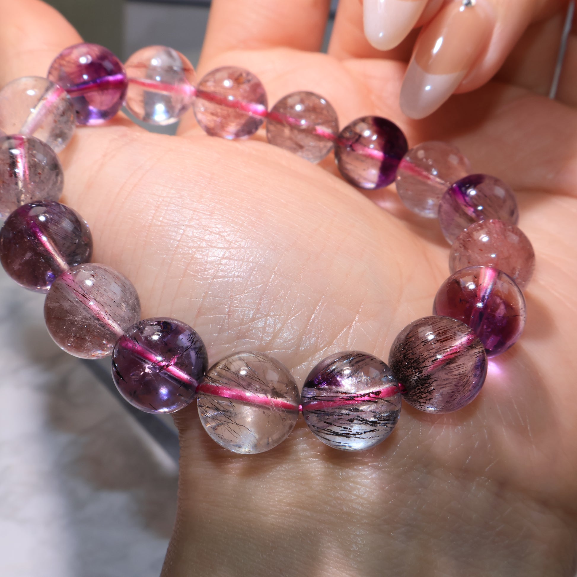Detailed view of Super Seven beads with rutile threads and deep amethyst hues.