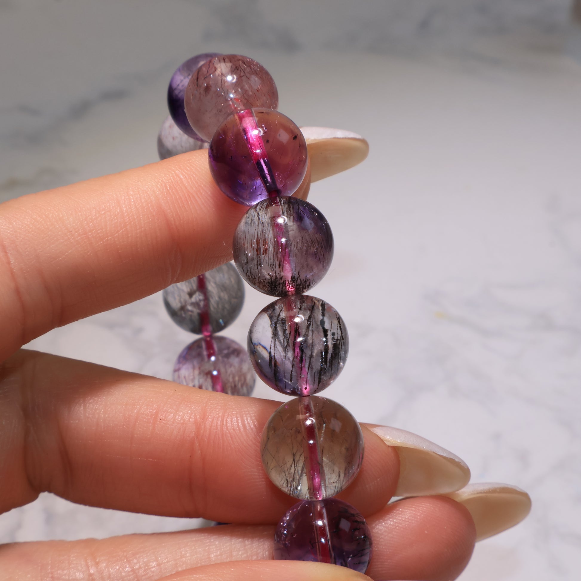 Close-up of beads showing smoky tones and black inclusions inside Super Seven.