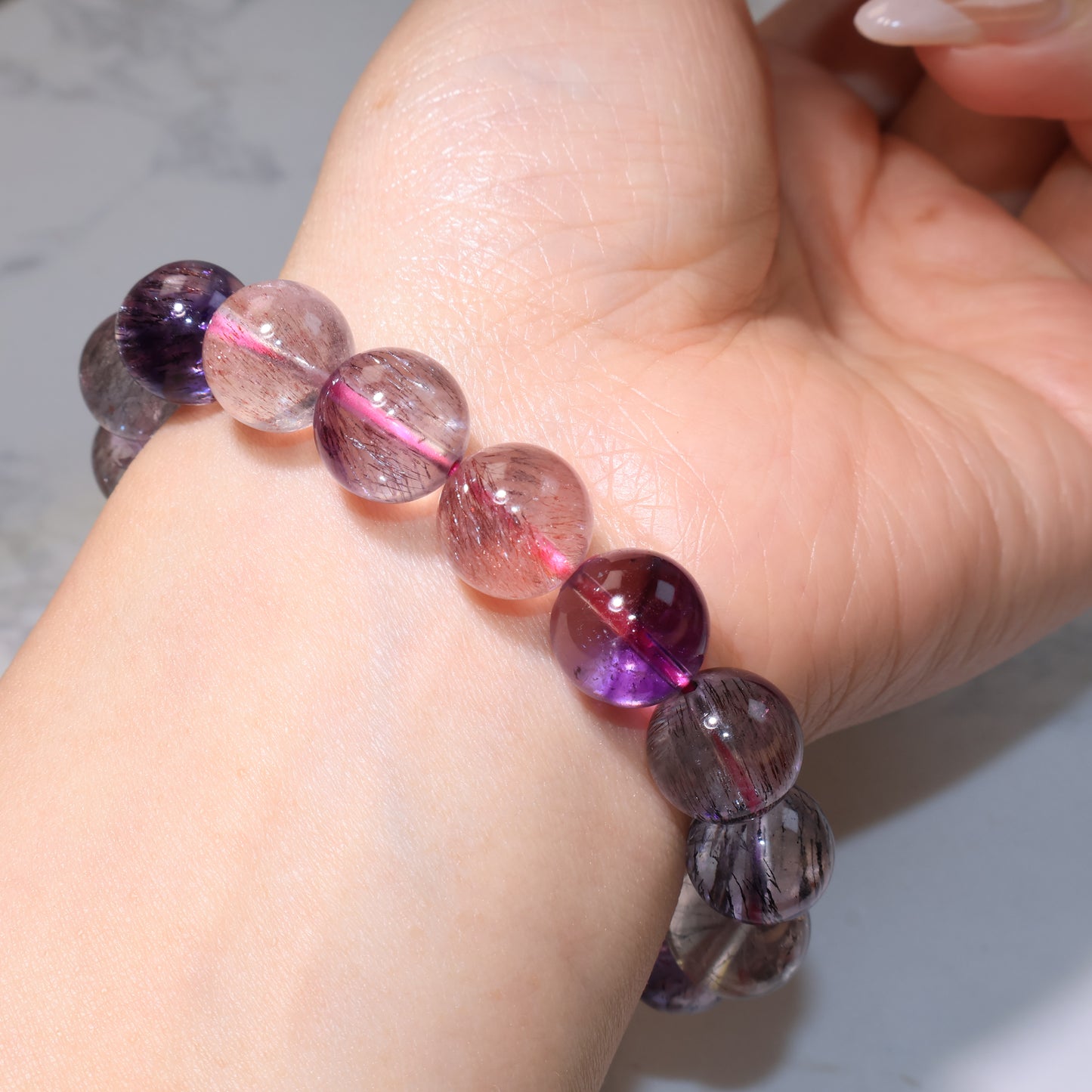 Wrist shot of the bracelet under lighting, showing purple and reddish inclusions.