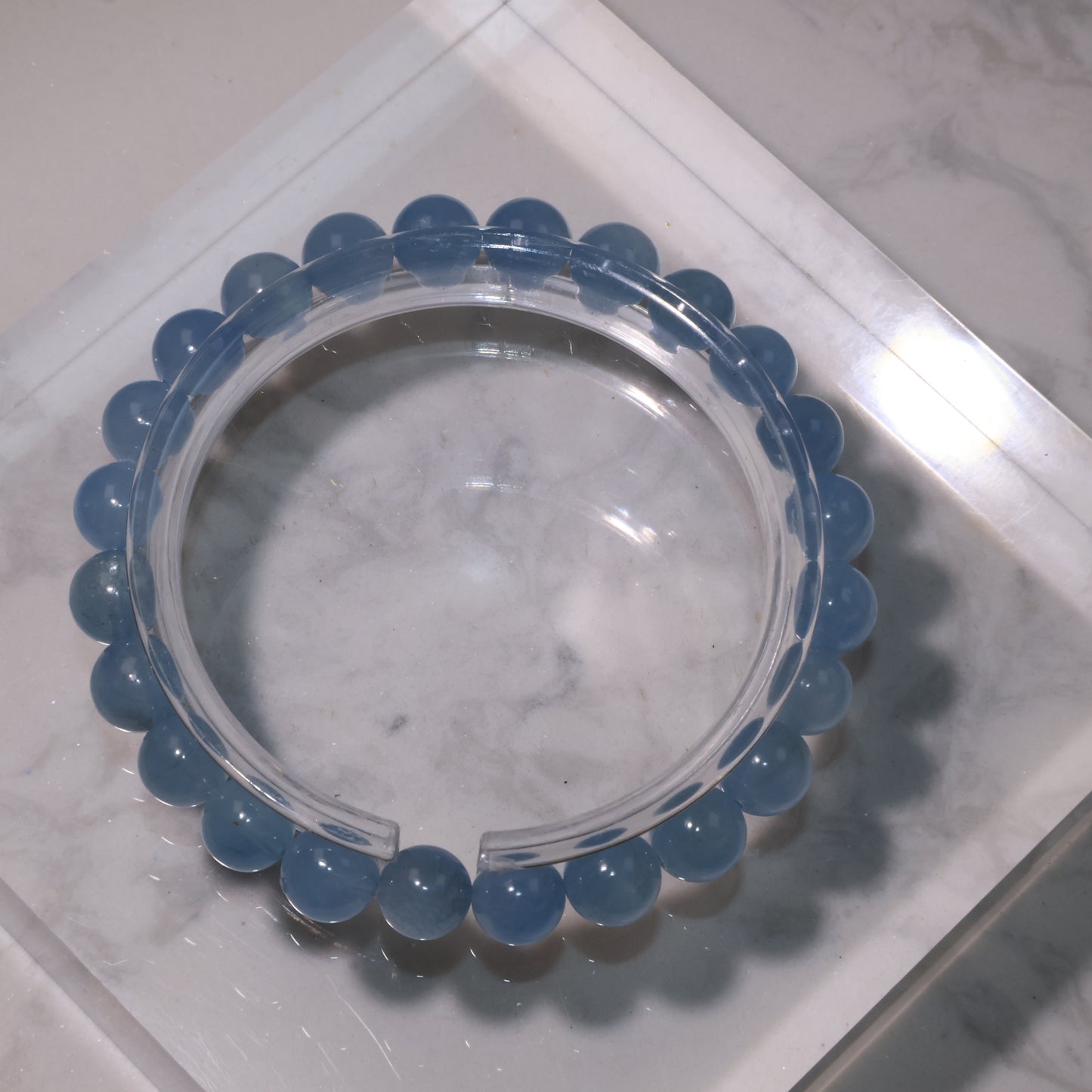 Aquamarine bracelet on clear display stand, showing uniform 8mm blue beads with natural translucency