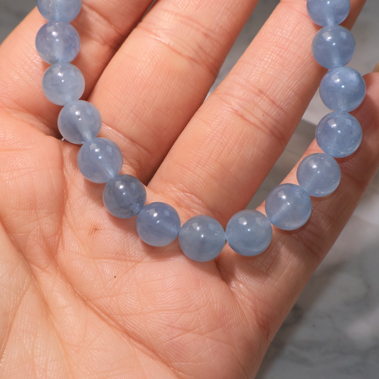 Close-up of aquamarine beads in hand, highlighting soft ocean-blue tones and natural inclusions
