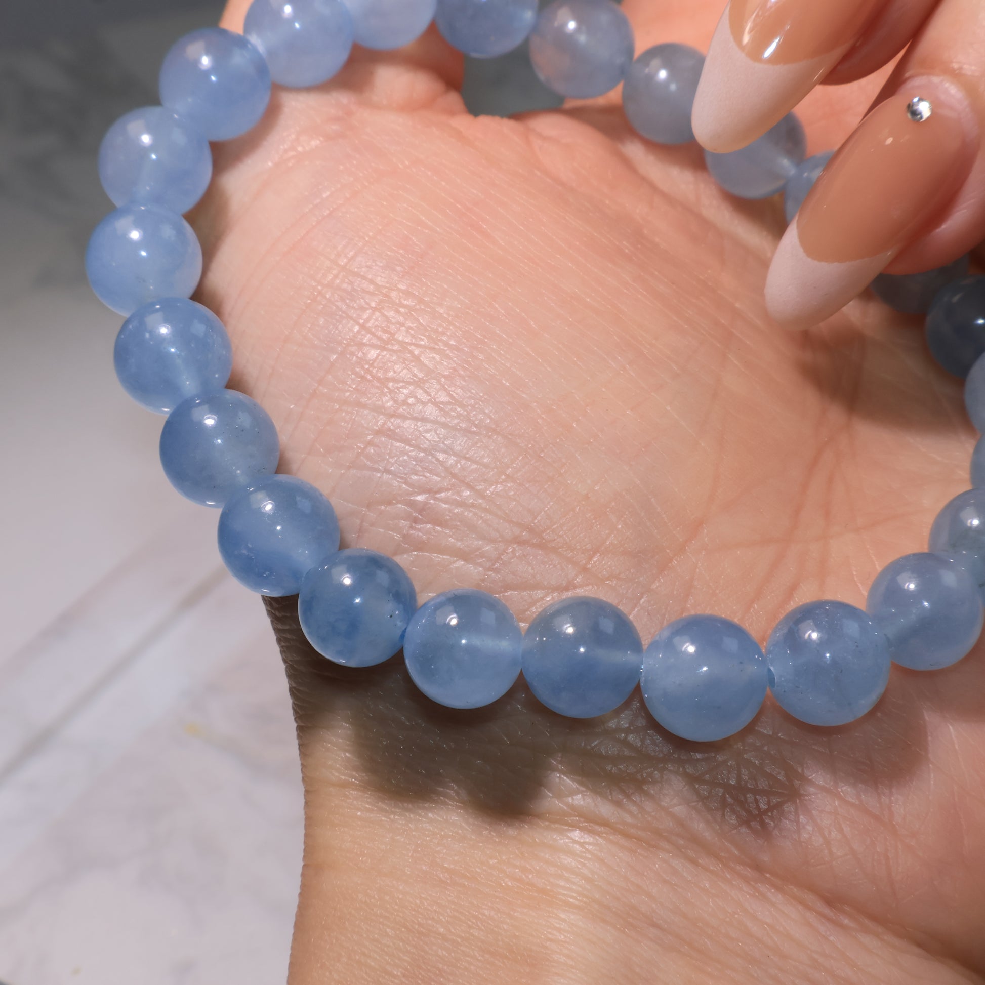 Detailed view of aquamarine bracelet under light, showing clarity, subtle ice cracks, and smooth polish