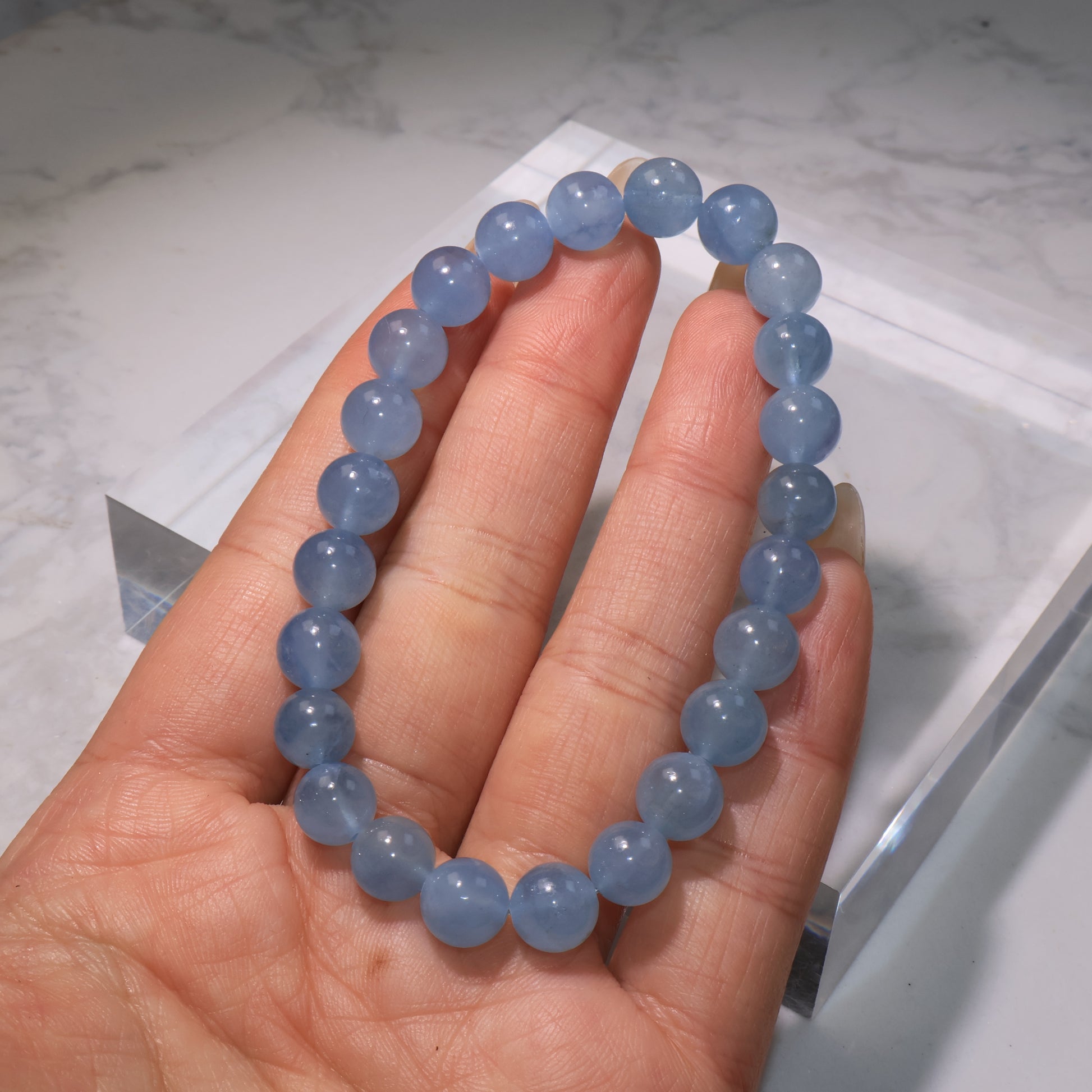 Full aquamarine bracelet stretched on hand, displaying consistent bead alignment and vibrant blue luster