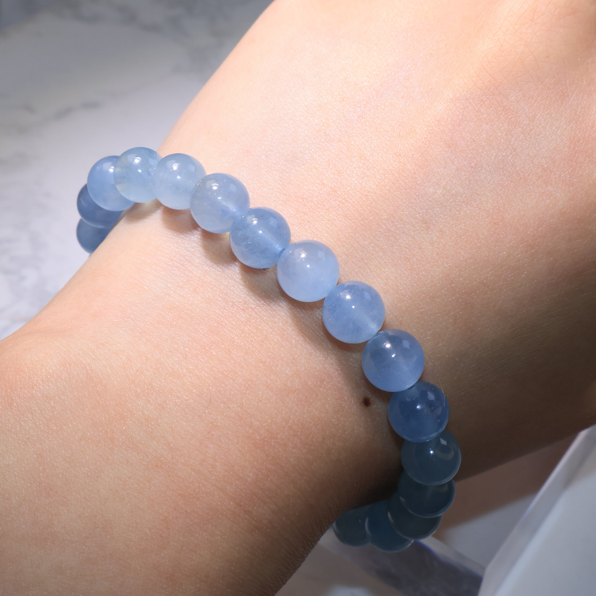 Aquamarine bracelet worn on wrist, natural ocean-blue beads radiating calm and soothing energy