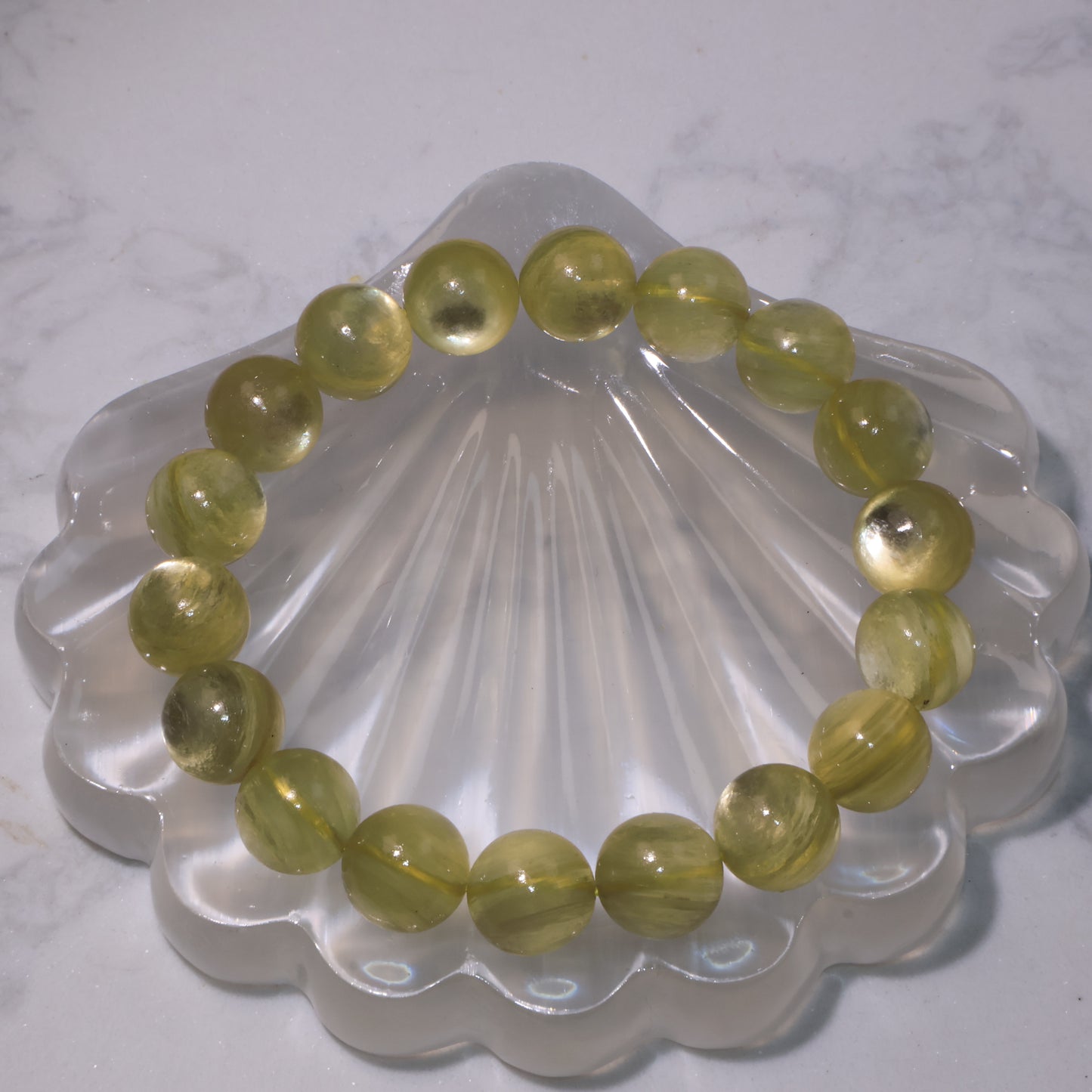 Golden Phlogopite bracelet on clear shell display, round 11mm beads glowing with golden shimmer