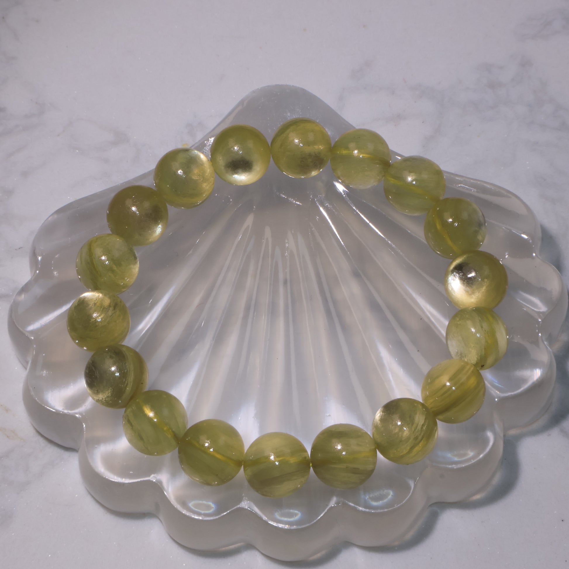 Golden Phlogopite bracelet on clear shell display, round 11mm beads glowing with golden shimmer
