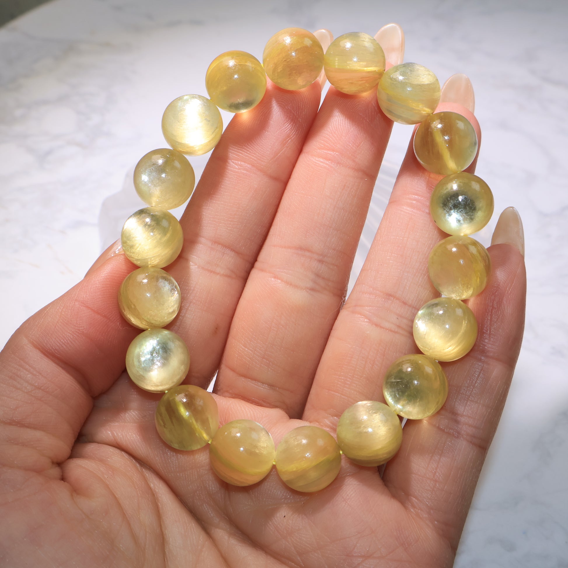 Close-up of golden phlogopite bracelet in hand, showing bright yellow-gold tones and reflective surface