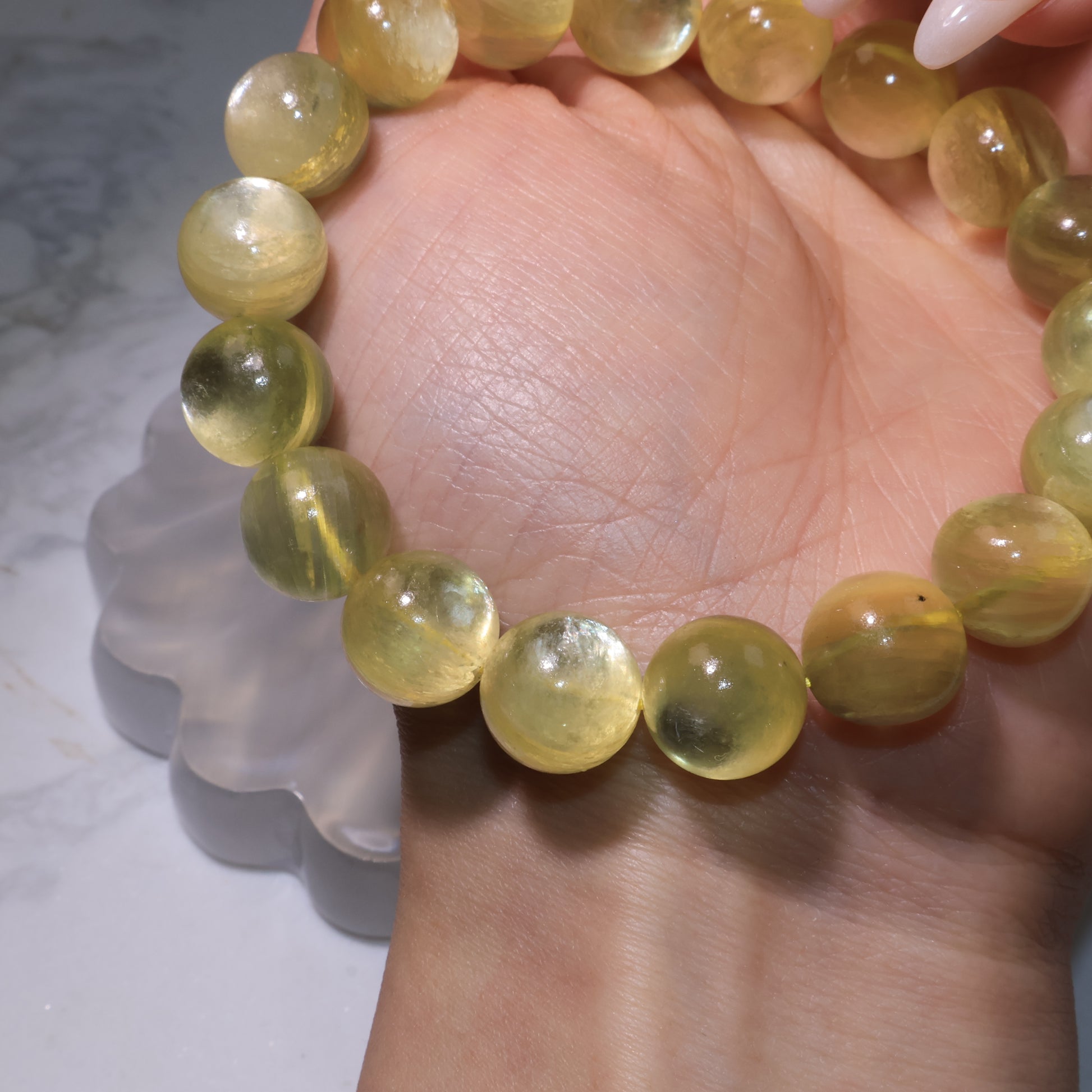 Detailed view of bracelet on palm, highlighting natural inclusions and golden reflections within the beads