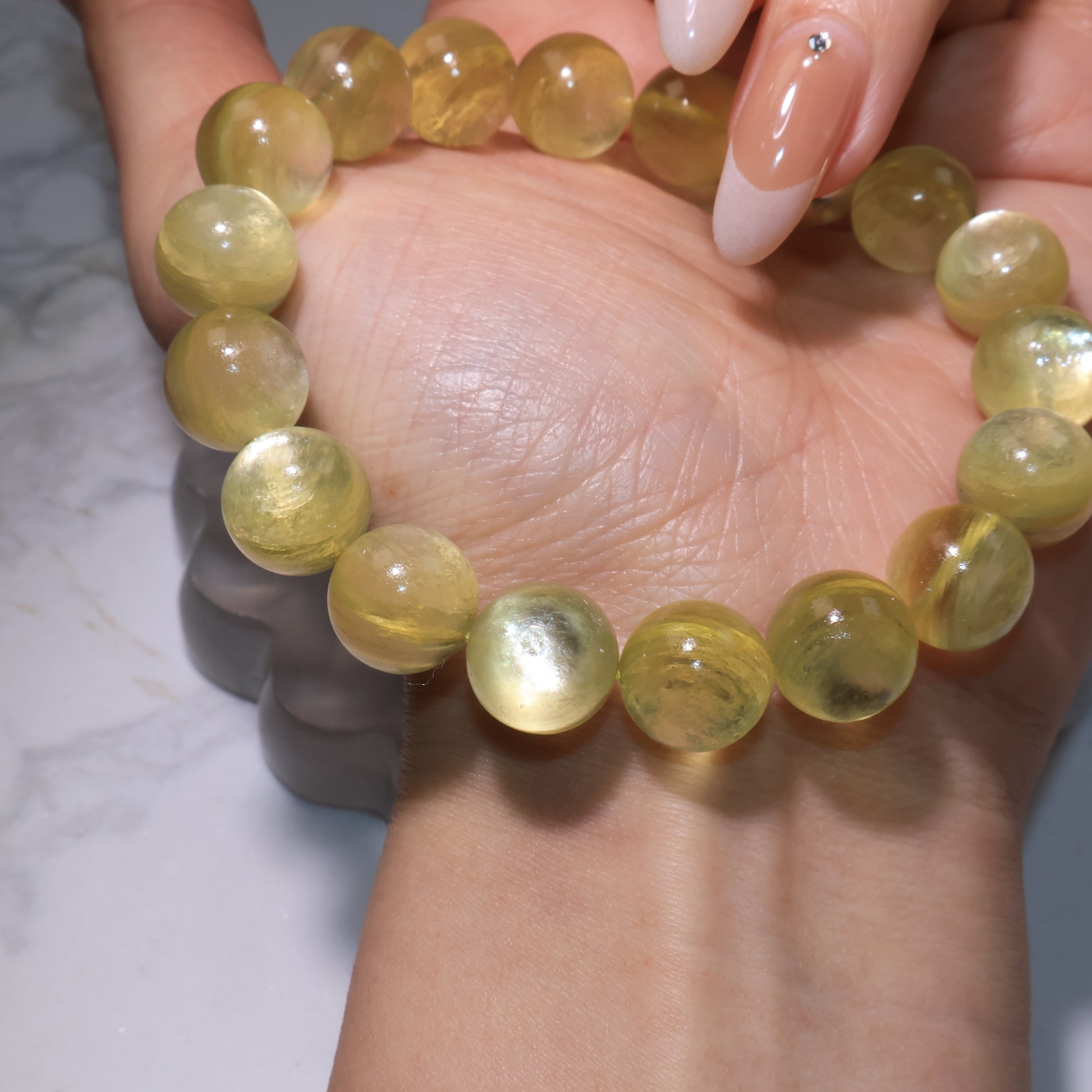 Golden phlogopite bracelet stretched on hand, showing round beads with luminous golden sheen