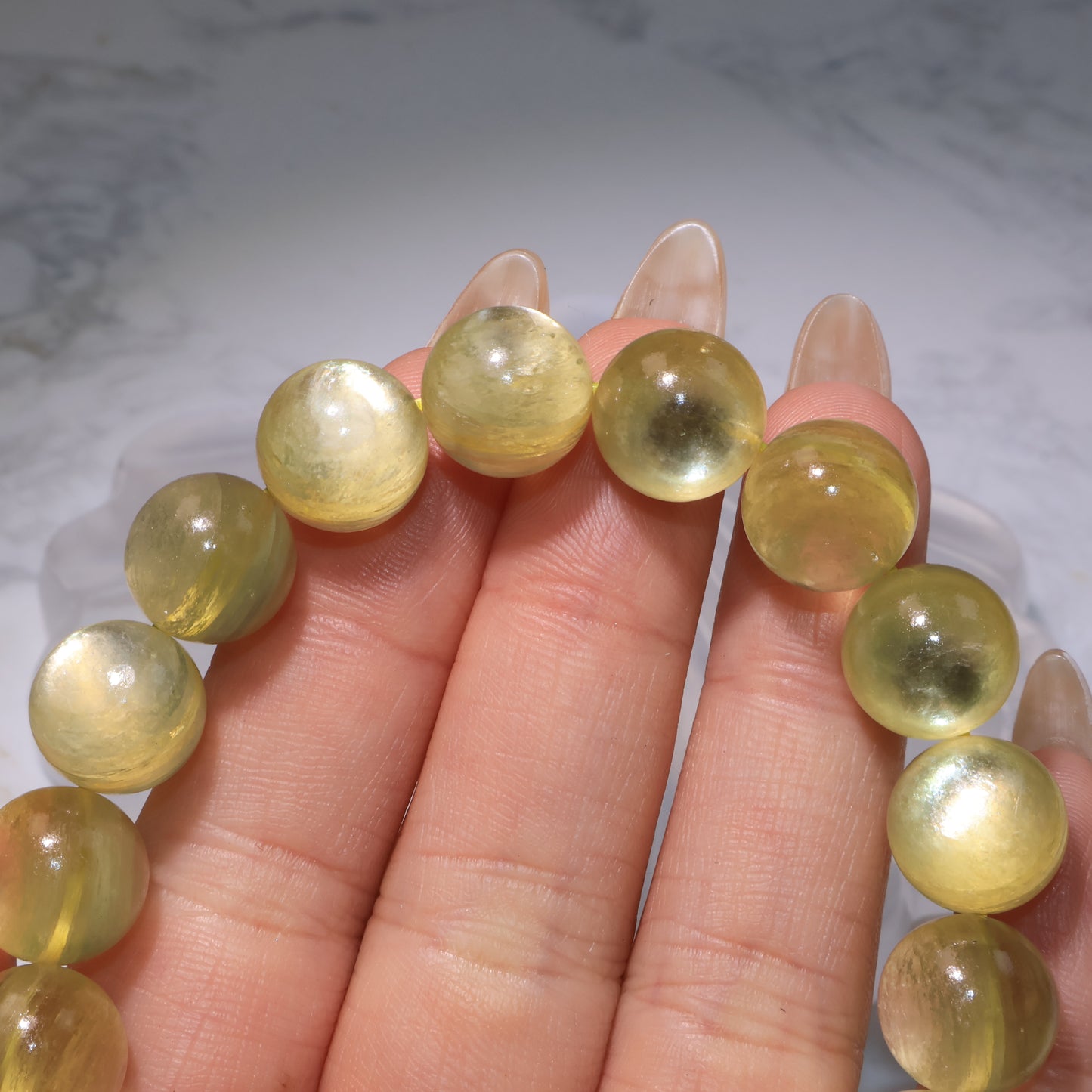 Close focus on bracelet beads under light, revealing translucent golden layers and internal texture