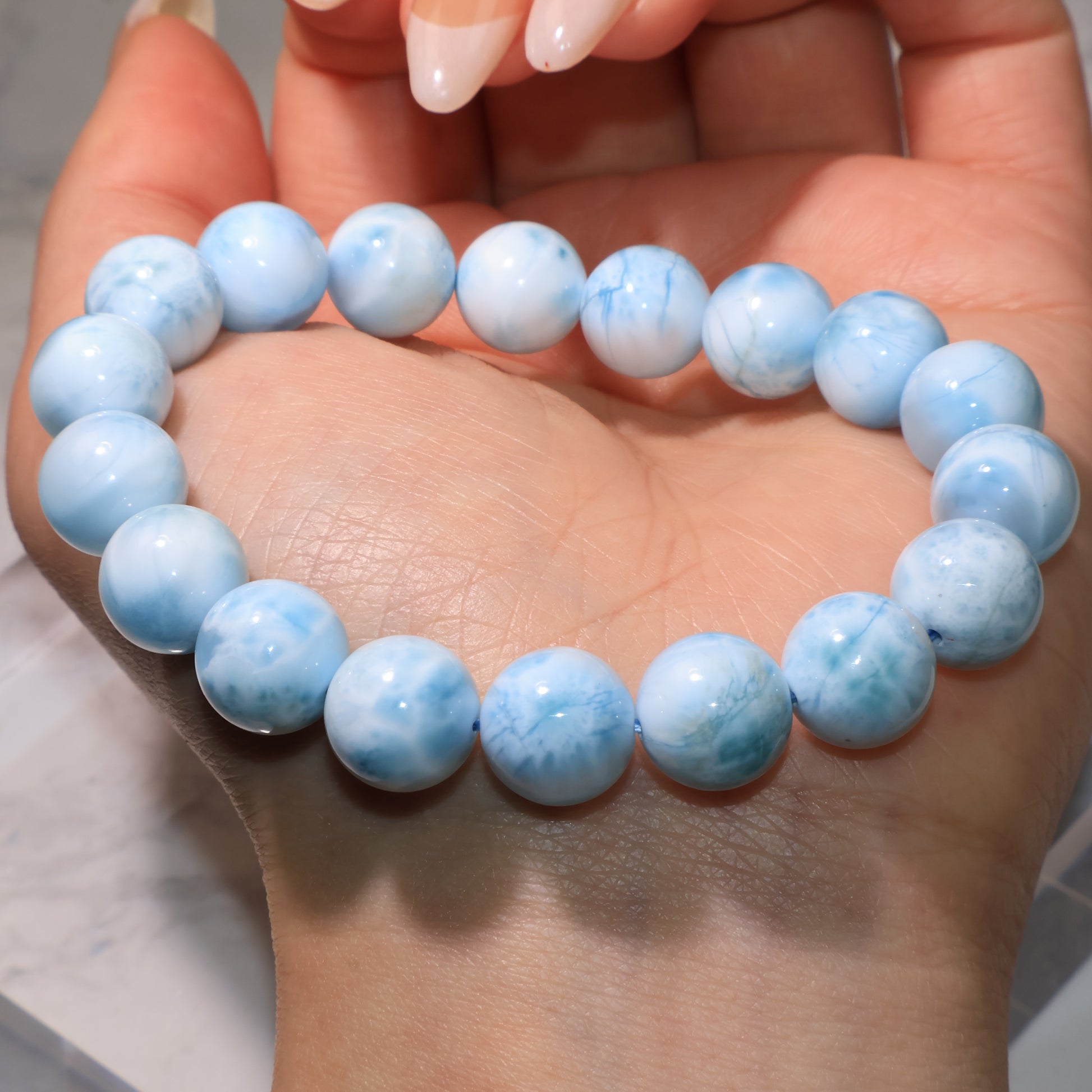 Larimar bracelet resting on the palm, round beads glowing under light.