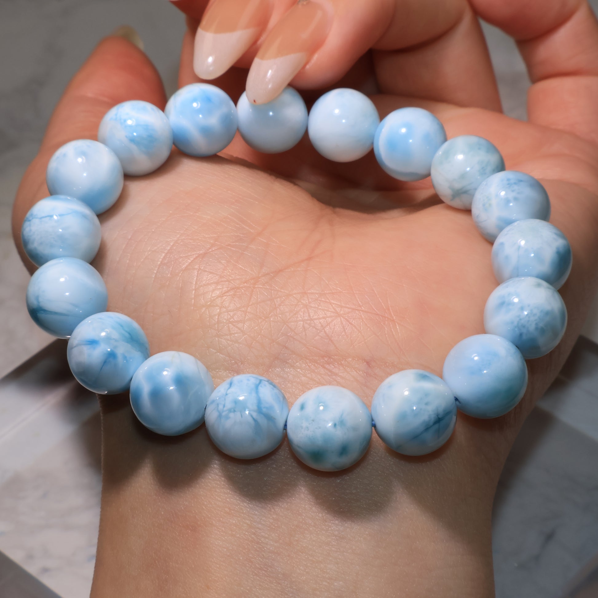 Close-up of Larimar bracelet with varied blue-white cloud patterns on beads.