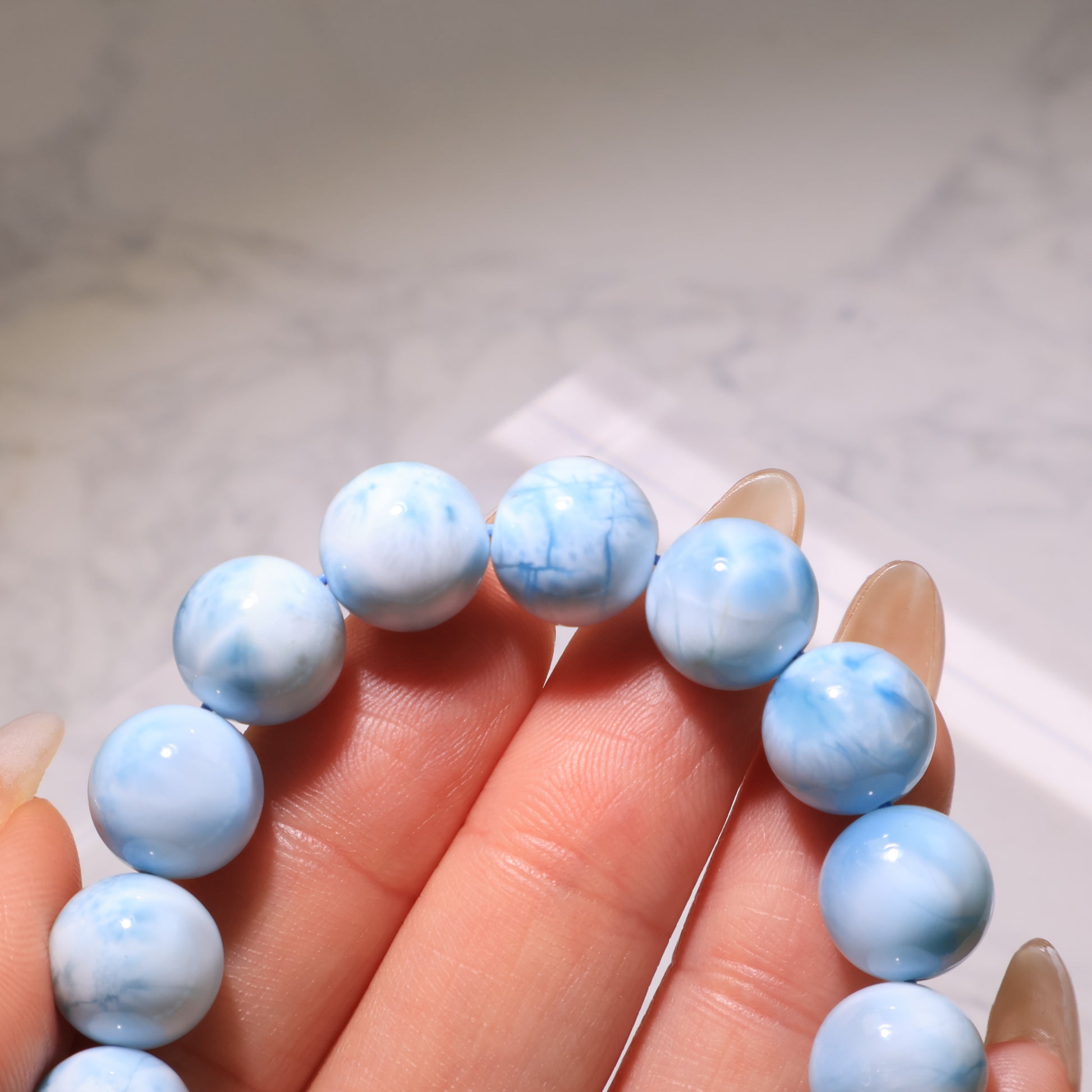 Macro shot of Larimar beads showing natural blue veins and white swirls.