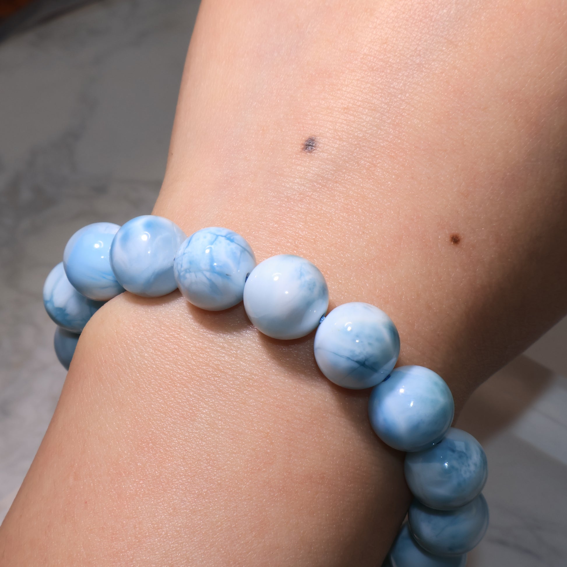 Larimar bracelet worn on wrist, sky-blue beads reflecting soft shine.