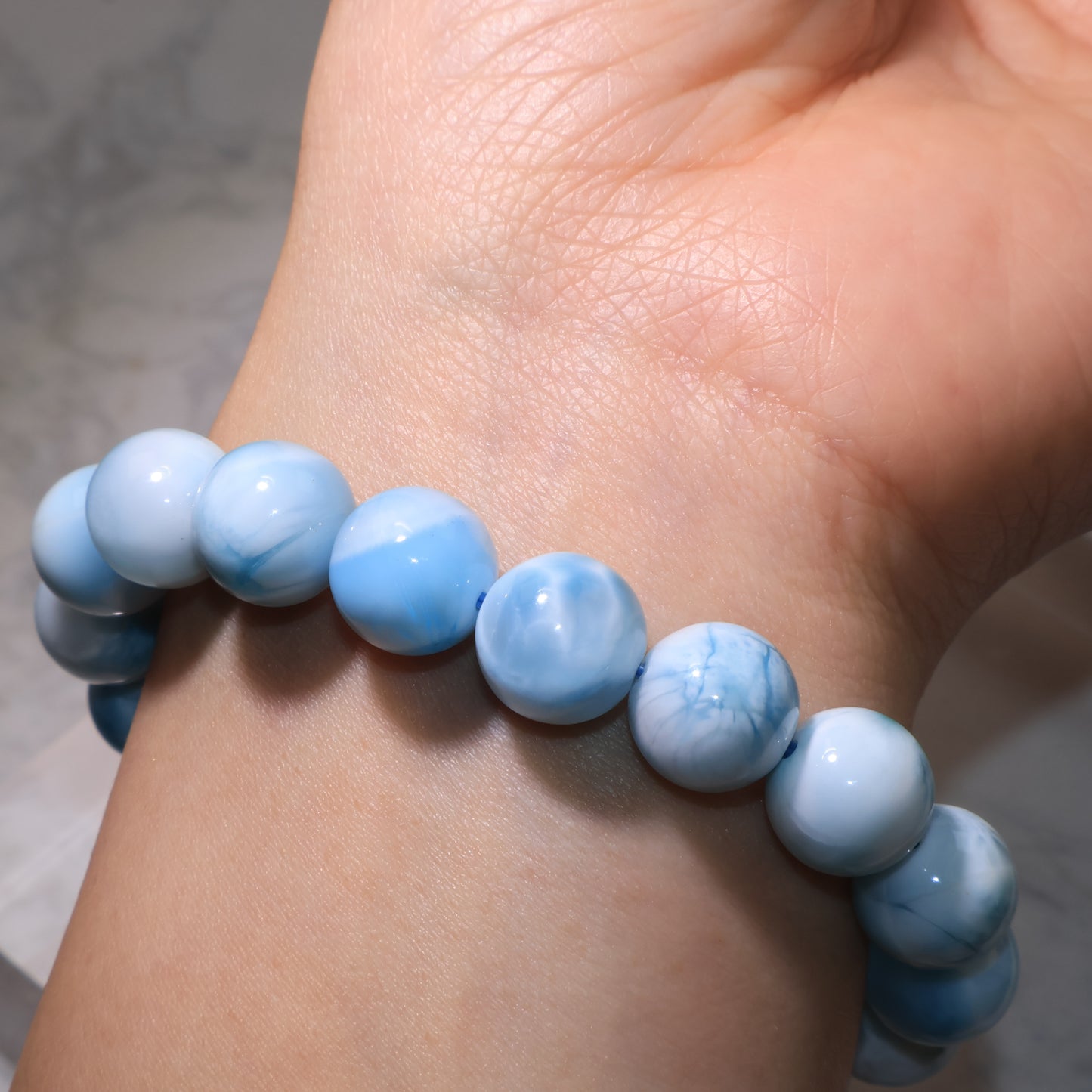 Side view of Larimar bracelet on wrist, showing polished round beads.