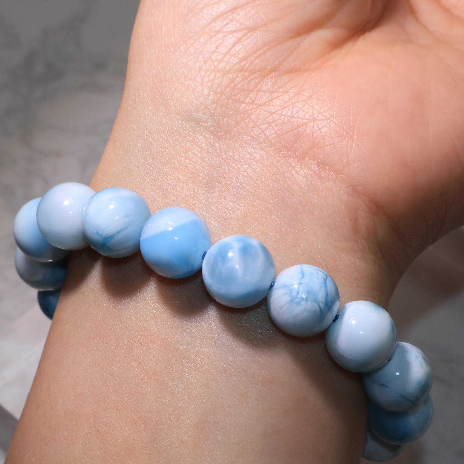 Side view of Larimar bracelet on wrist, showing polished round beads.