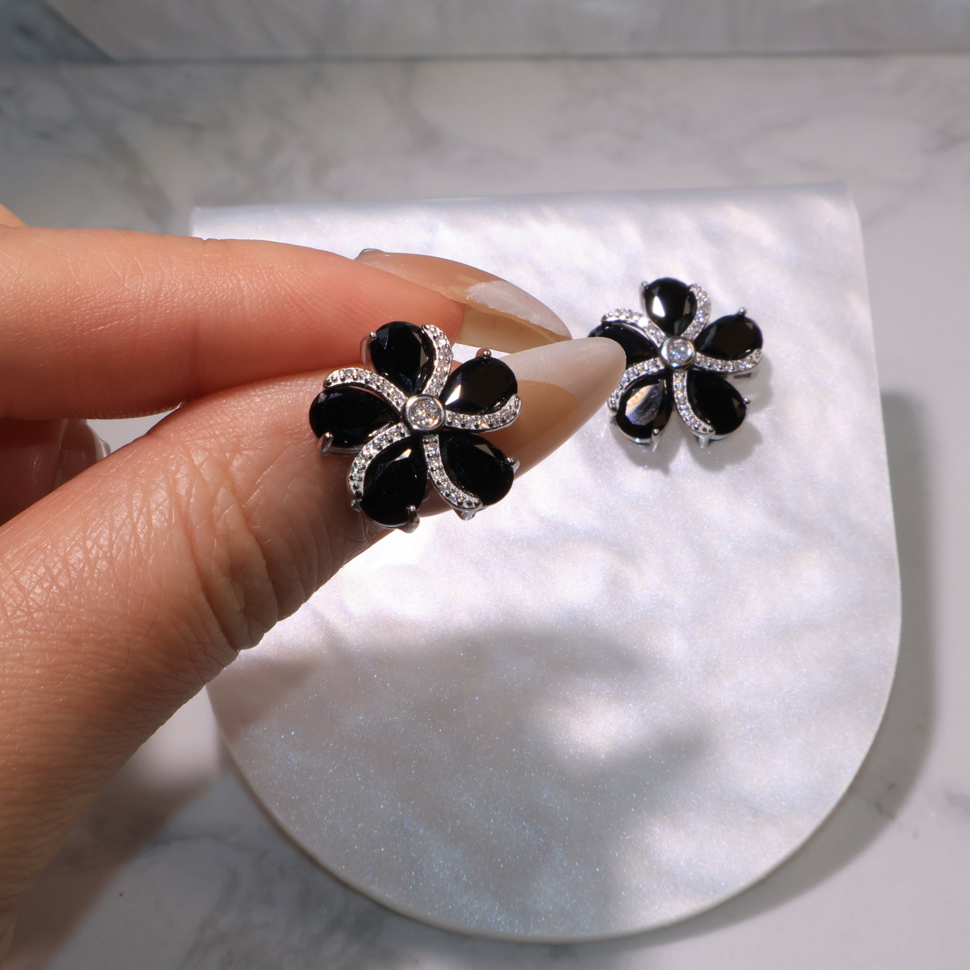 Hand holding one earring to show size, craftsmanship, and gemstone shine.