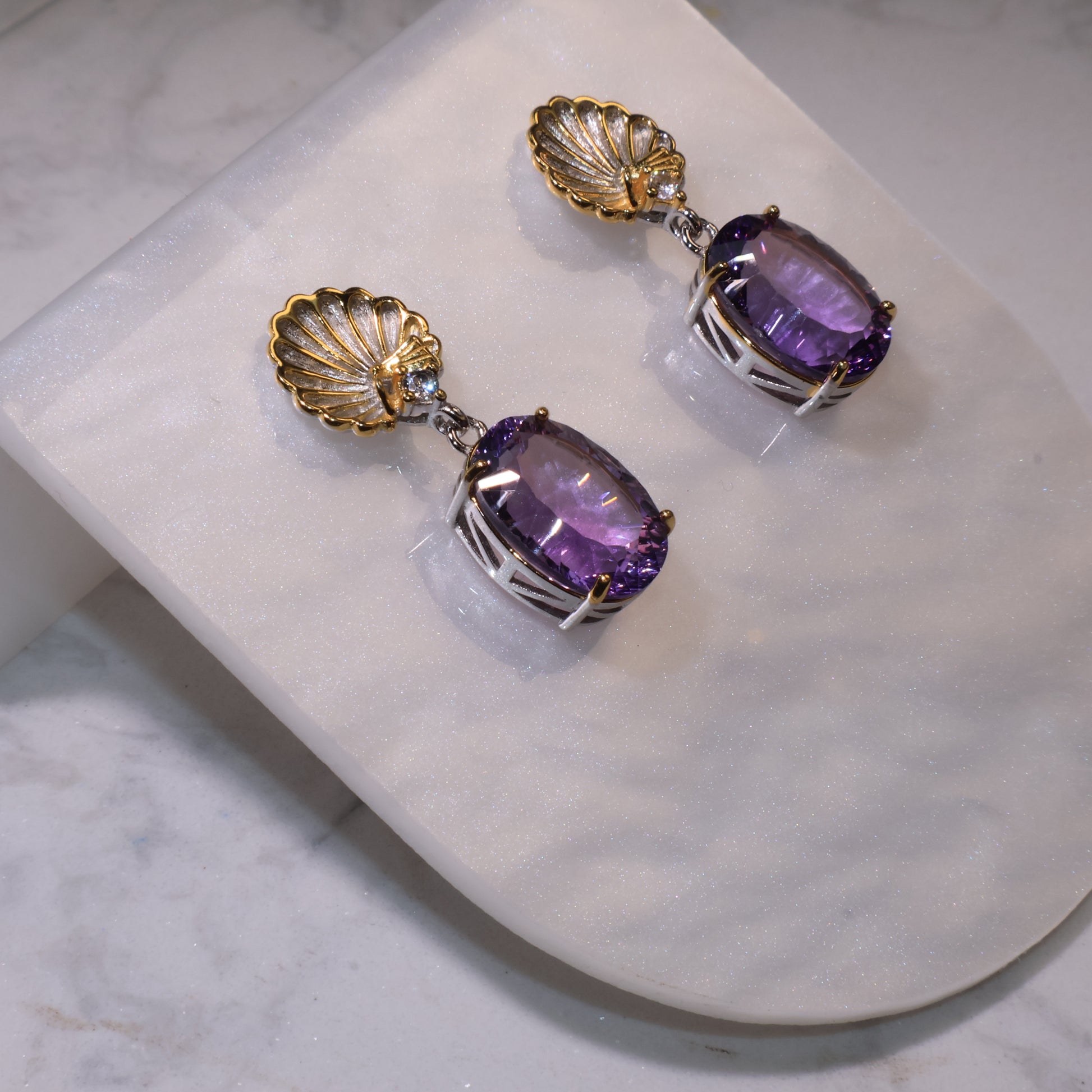 Side view showing the 3D structure of the earrings, highlighting the silver prong setting and amethyst transparency.