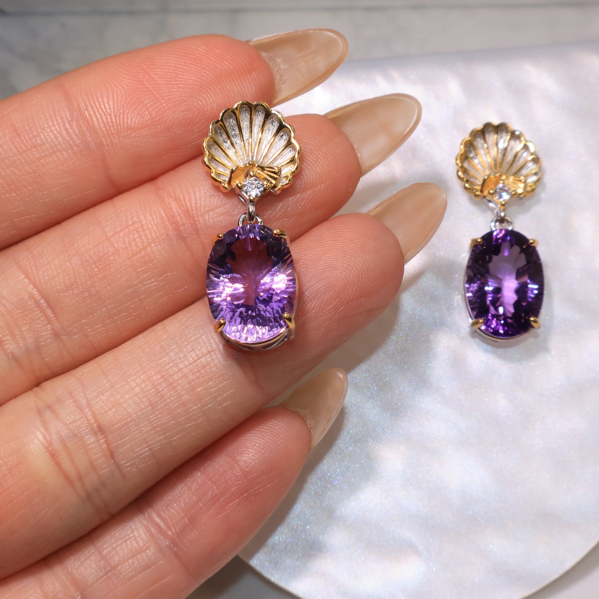 A hand holding one of the earrings to show size and gemstone clarity.