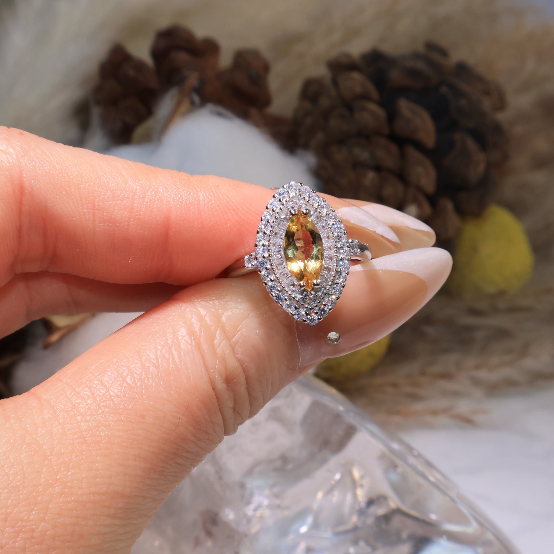 Close-up of the marquise citrine ring held by hand, highlighting the vivid yellow tone and sparkling halo.