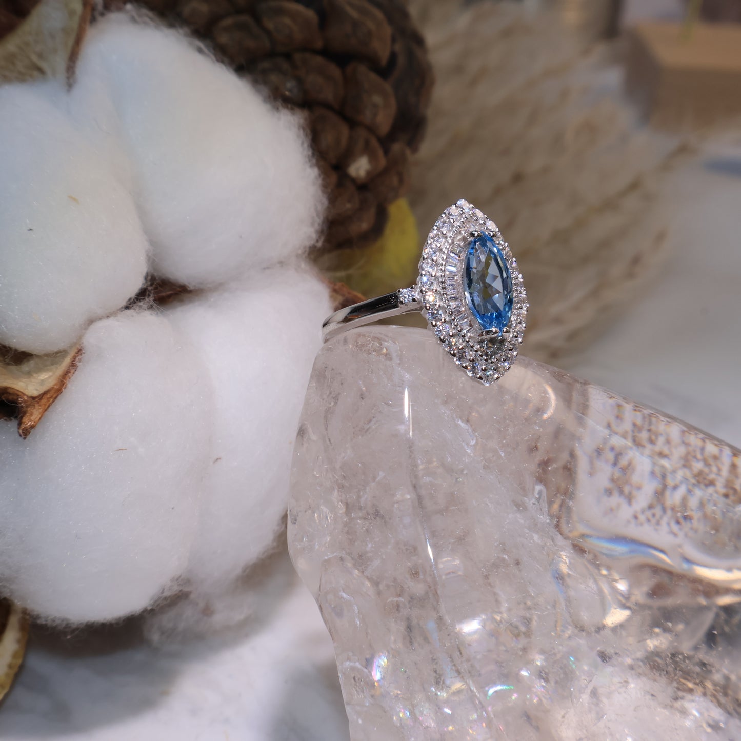 Side view of the blue topaz halo ring showing the layered zircon design and elegant silver band.