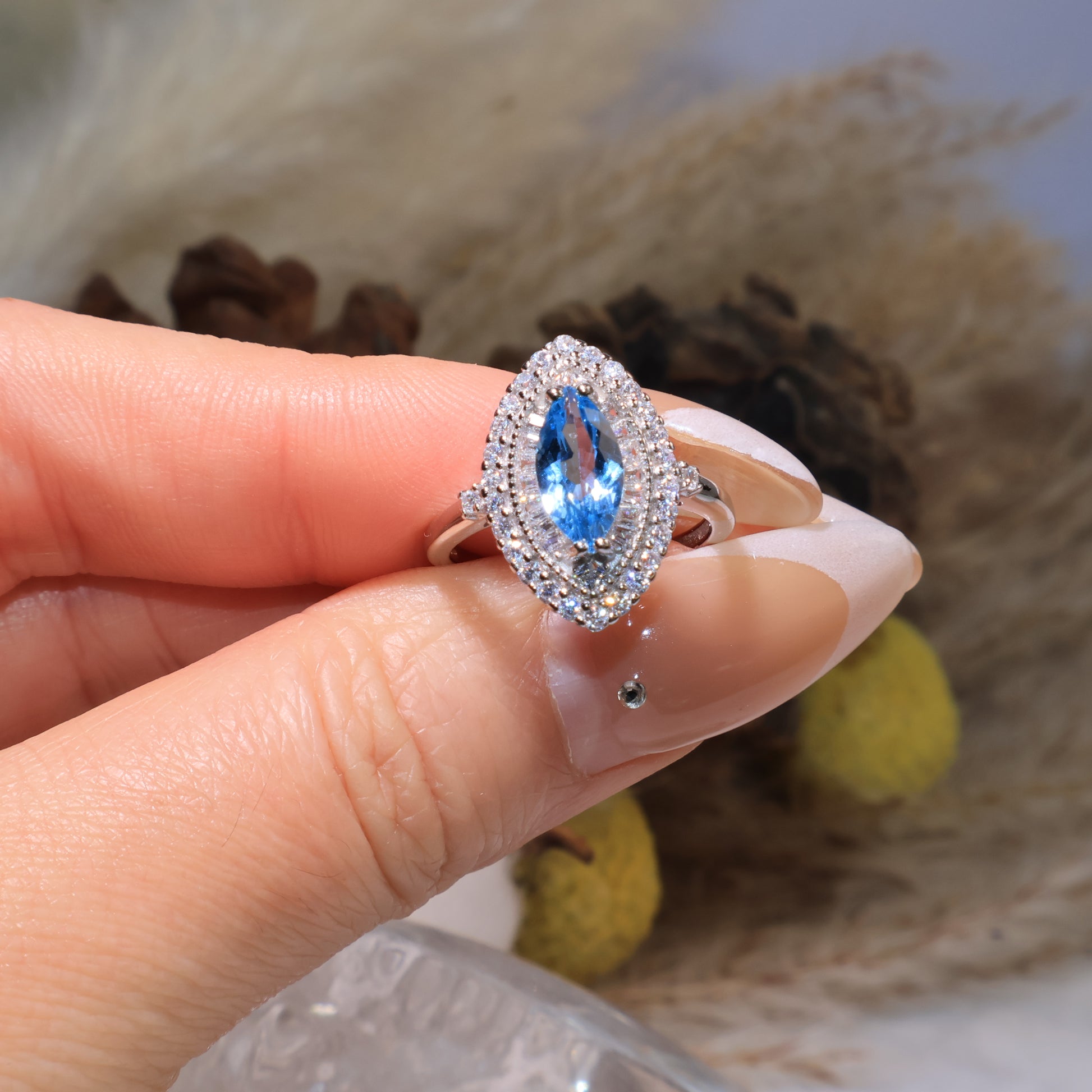 Close-up of the marquise blue topaz ring held by hand, capturing its radiant clarity and fine craftsmanship.