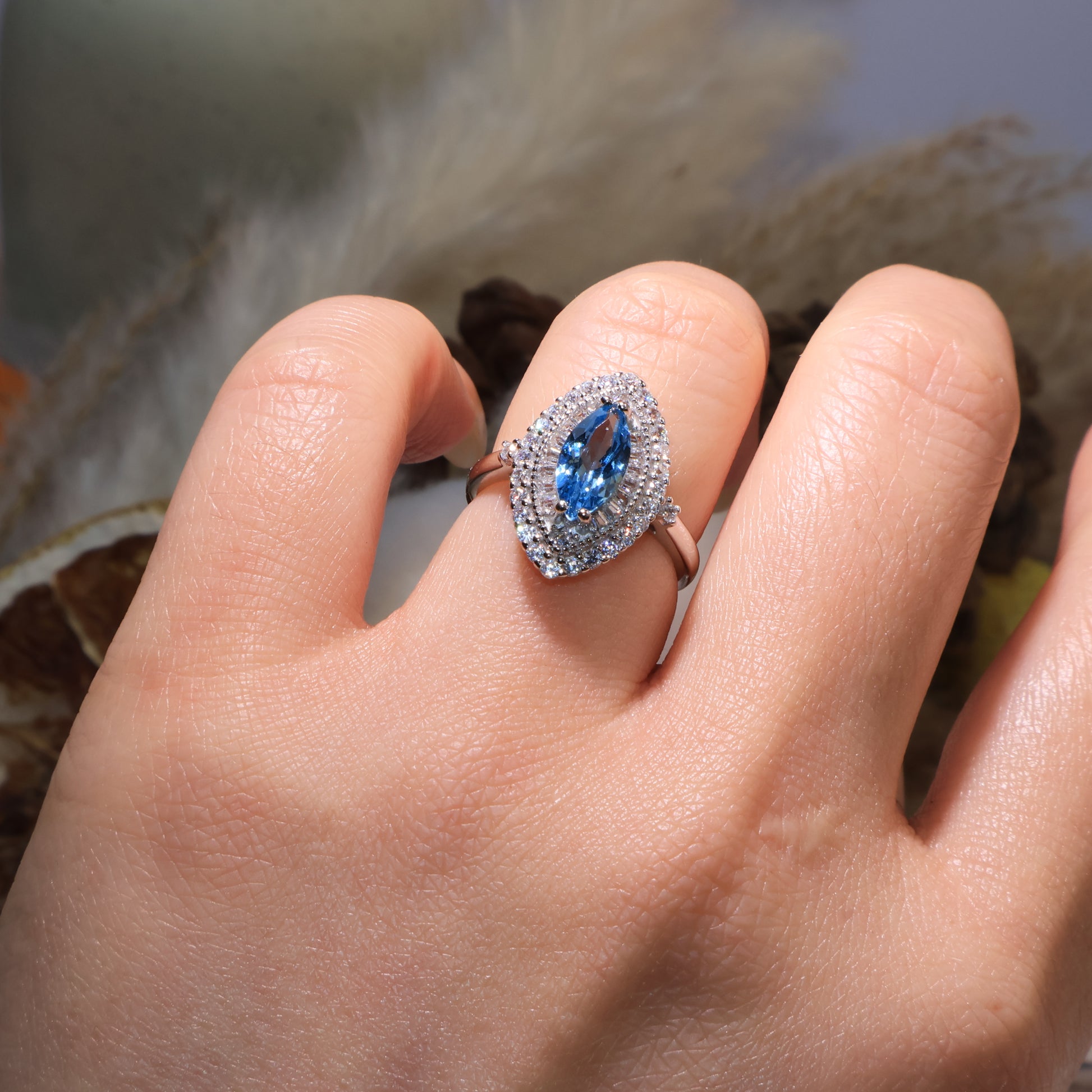 Blue topaz ring worn on hand, reflecting serene ocean tones under soft lighting.