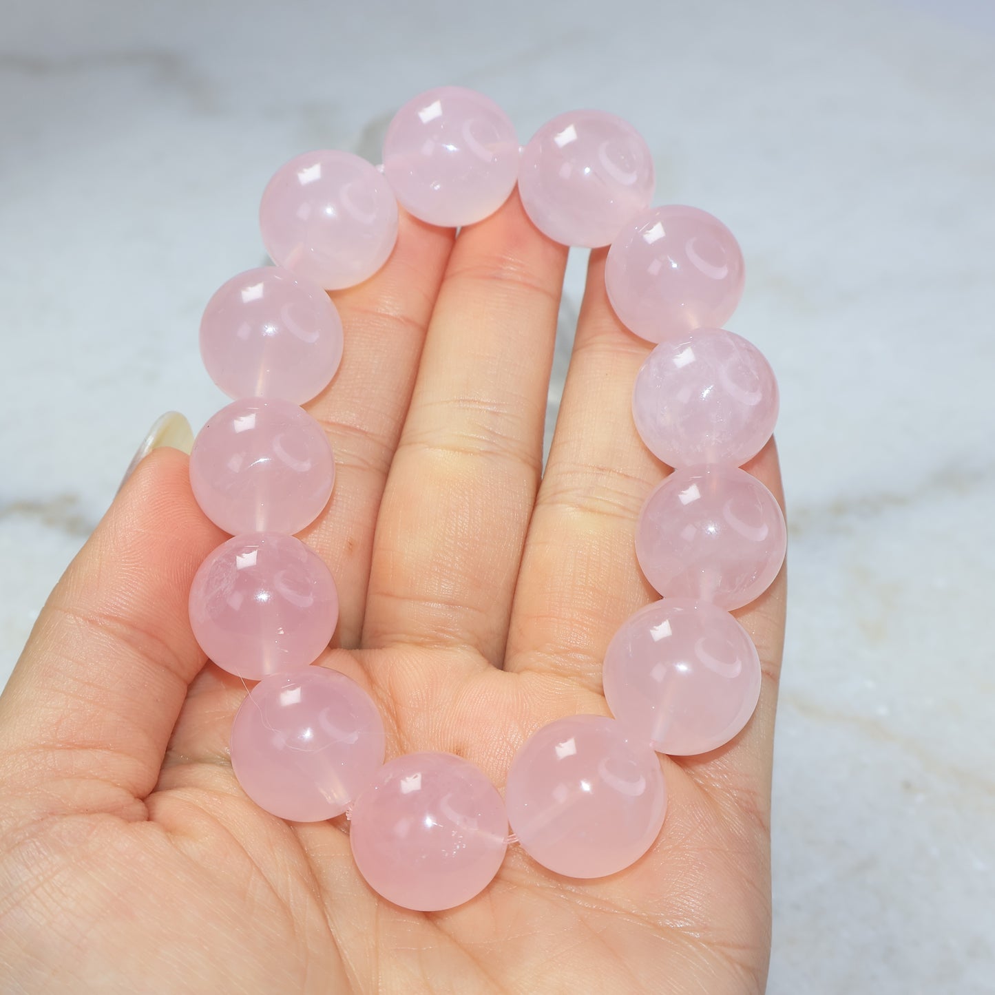 Large bead rose quartz bracelet held in hand showing soft translucent pink colour