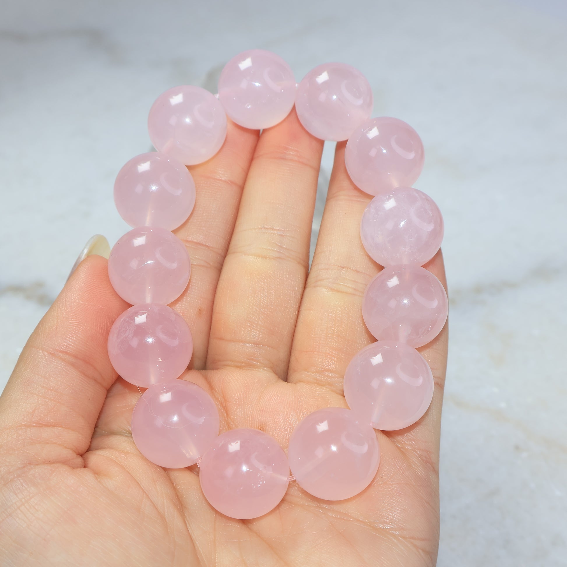 Large bead rose quartz bracelet held in hand showing soft translucent pink colour