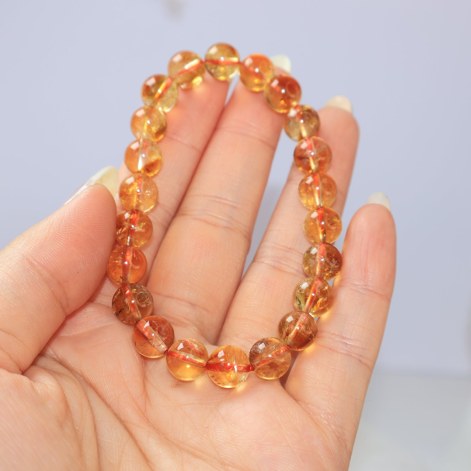  Hand holding golden Citrine bracelet with translucent honey tones