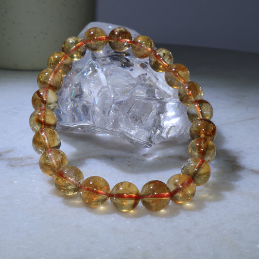    Natural 8mm Citrine crystal bracelet displayed with clear quartz stand