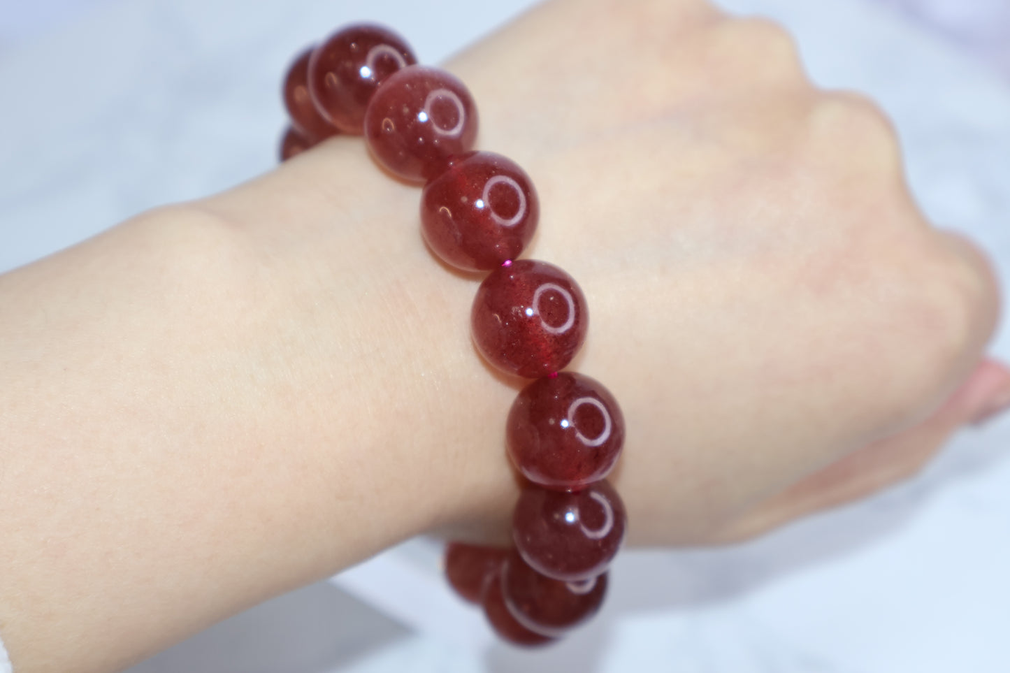Heart Awakening 14mm strawberry quartz bracelet worn on wrist – glossy deep red crystal beads from Brazil, shown for size and fit demonstration.