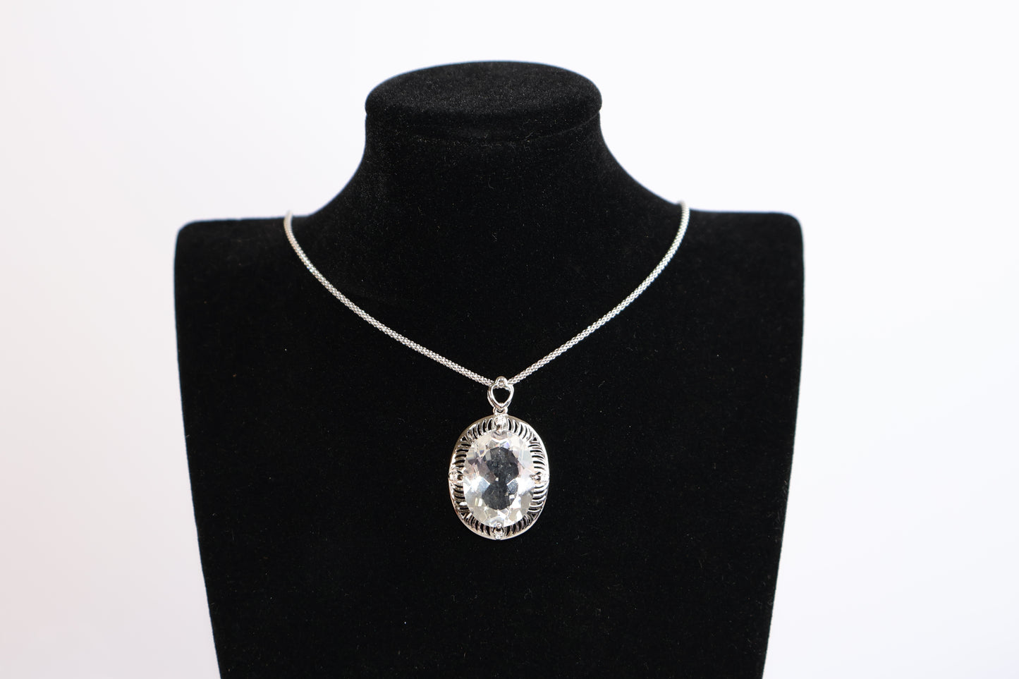 Clear quartz pendant displayed on velvet bust for scale and styling