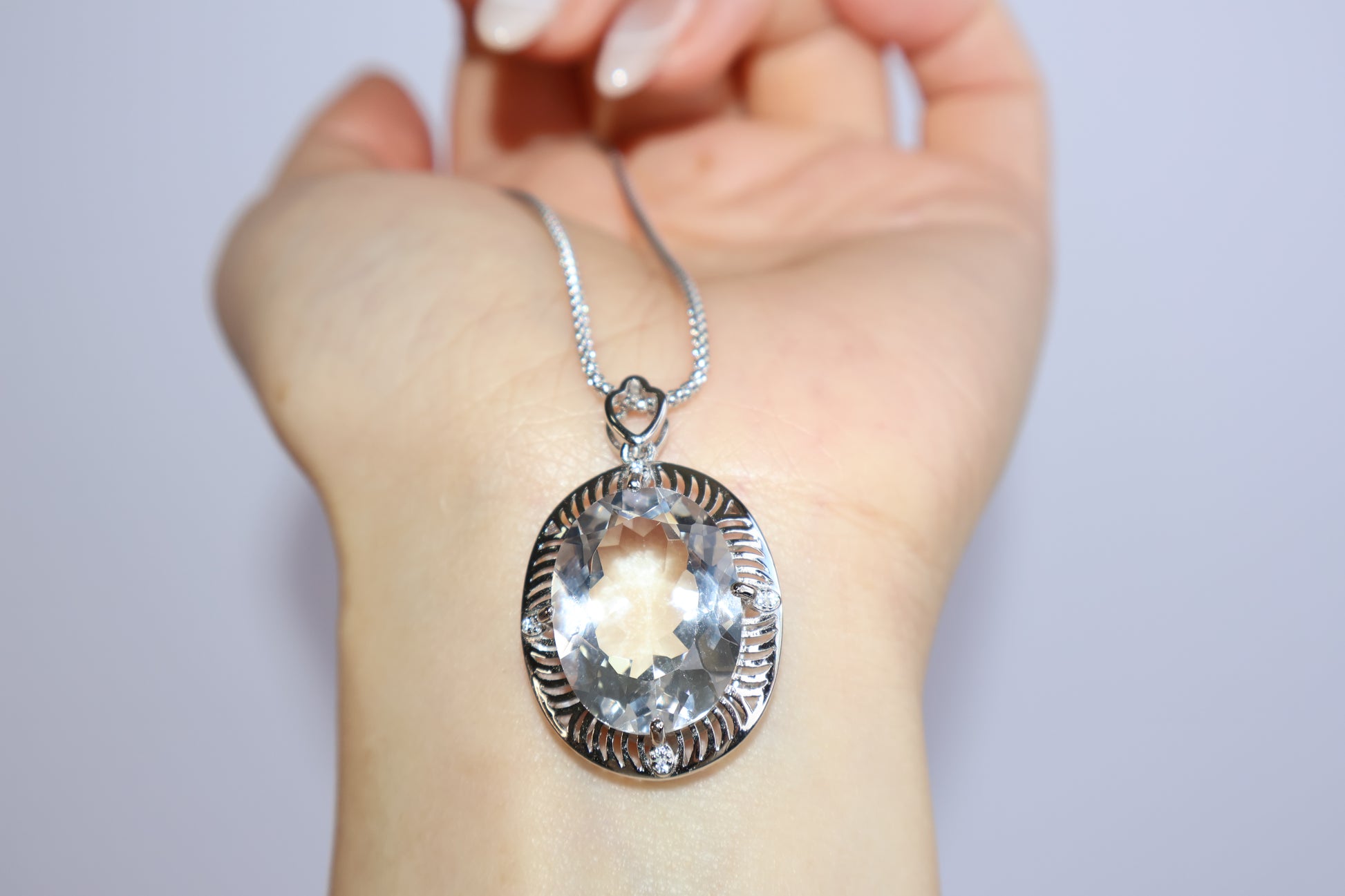 Elegant clear quartz crystal pendant shown on hand for size reference