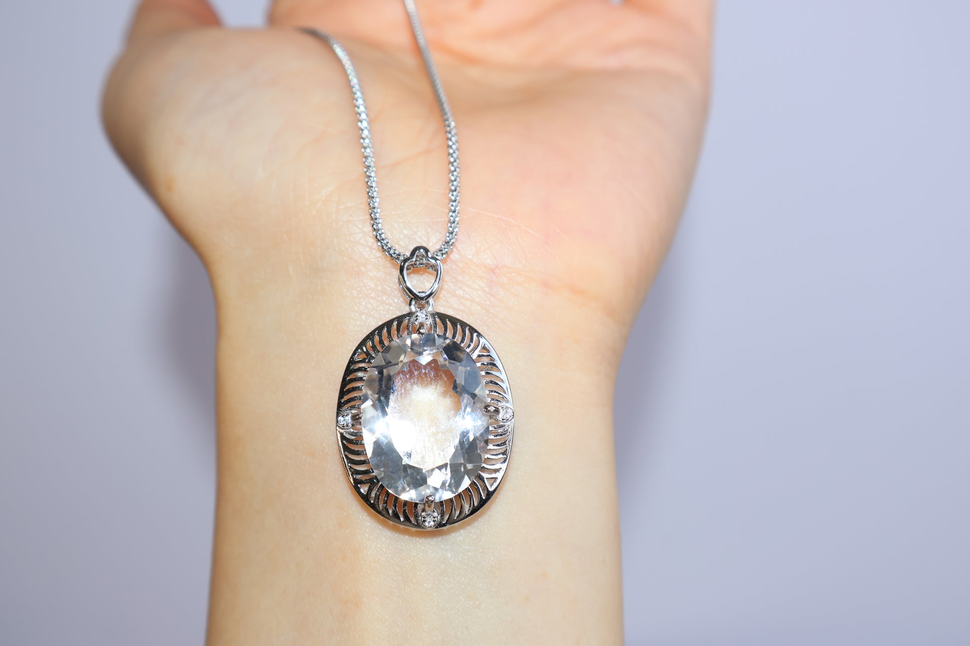 Close-up of clear quartz pendant showcasing faceted cut and silver setting details