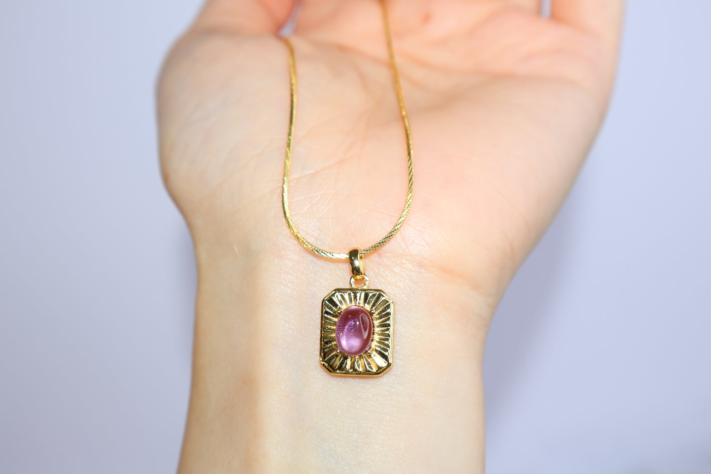 Oval amethyst pendant shown on hand for size reference