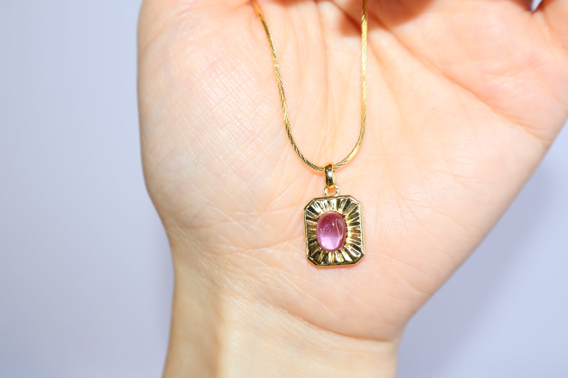 Close-up of purple amethyst pendant with gold bezel