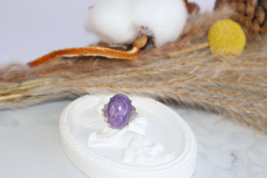 Charoite gemstone ring in 925 sterling silver on decorative white tray with cotton background