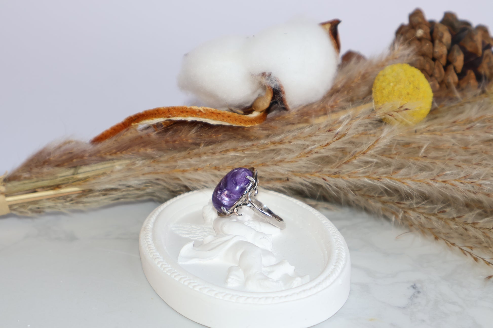 Natural charoite ring with swirling patterns resting on angel tray