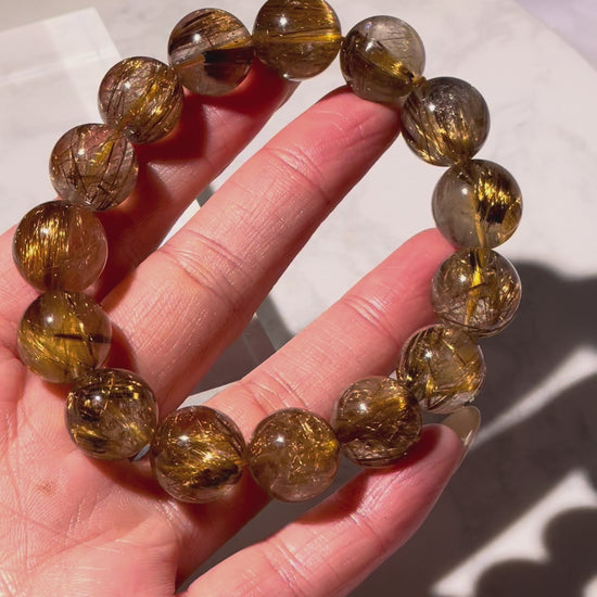 Video showing the full 360° view of golden brown rutilated quartz bracelet with sparkling rutile threads inside each bead.
