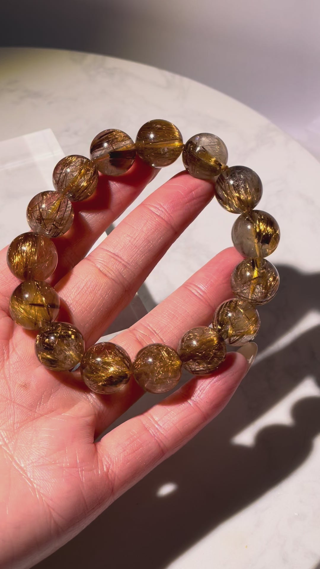 Video showing the full 360° view of golden brown rutilated quartz bracelet with sparkling rutile threads inside each bead.