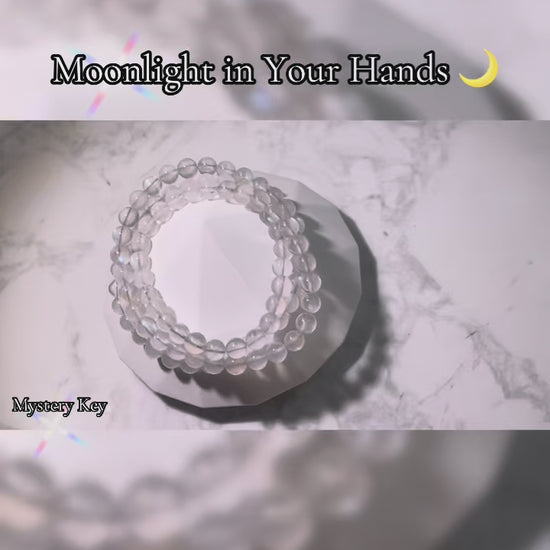 Video showcasing the Intuition & Calm Moonstone Bracelet (6mm triple wrap, India). The bracelet is displayed in different angles—on a crystal plate, held in hand, and worn on the wrist—highlighting its translucent beads and glowing blue flashes, symbolizing intuition, emotional balance, and inner calm.