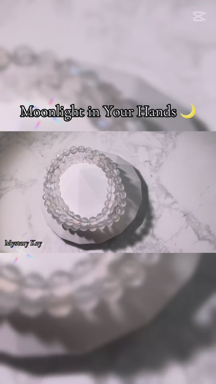 Video showcasing the Intuition & Calm Moonstone Bracelet (6mm triple wrap, India). The bracelet is displayed in different angles—on a crystal plate, held in hand, and worn on the wrist—highlighting its translucent beads and glowing blue flashes, symbolizing intuition, emotional balance, and inner calm.