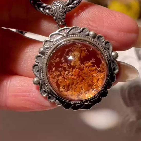 Video showing a 20mm Phantom Quartz pendant with moss-like inclusions, set in an ornate S925 vintage silver frame. The pendant sparkles under light as it moves, highlighting its dreamy internal patterns. Chain not included.
